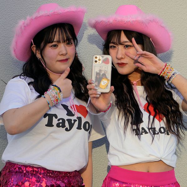 Taylor Swift på scen delad med bild på två japanska Swift-fans i Japan med rosa cowboyhattar på sig.
