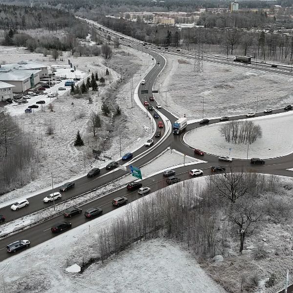 Delad bild av två sektioner. Den vänstra sektionen visar en person bakom en SVT-mikrofon i vinterkläder, medan den högra sektionen visar en flygbild av en trafikstockning på en snötäckt väg.