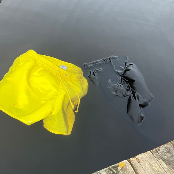 Till vänster: Caroline Olausson, kommunikatör på Södra älvsborgs räddningstjänstförbund, står vid en sjö. Till höger: Ett par neongula och ett par svarta badbyxor i vattnet.