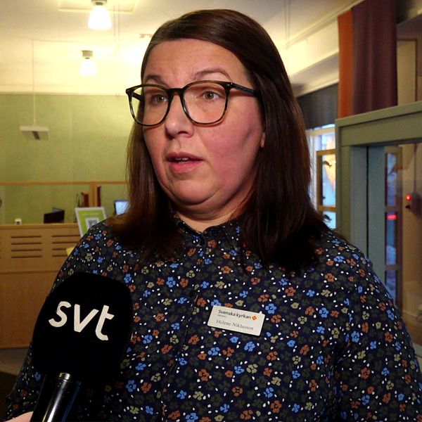 till vänster syns snötäckta gravstenar. Till höger står Helene Niklasson, chef för informationsservice hos Svenska kyrkan, iklädd en blommig blus, glasögon och brunt hår.