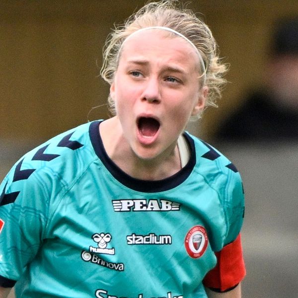 Fotbollsspelare i grönblå matchdräkt på planen under match.