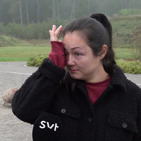 En kvinna torkar en tår. Hon står i en lekpark i Fullerö.