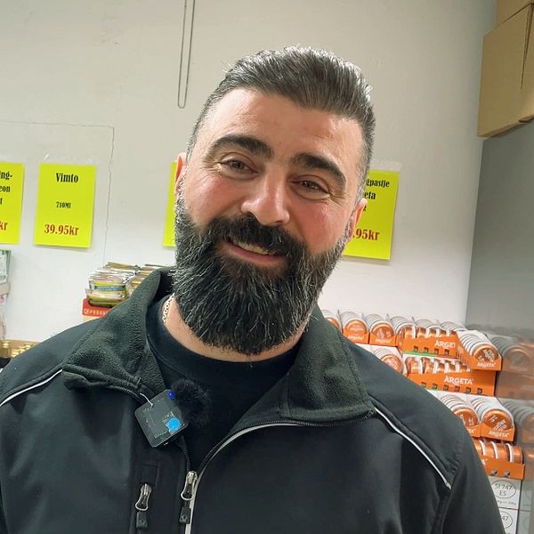 Matvarubutik med staplade produkter och person i bakgrunden.