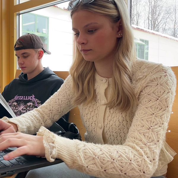 Två unga personer vid var sin dator i skolmiljö