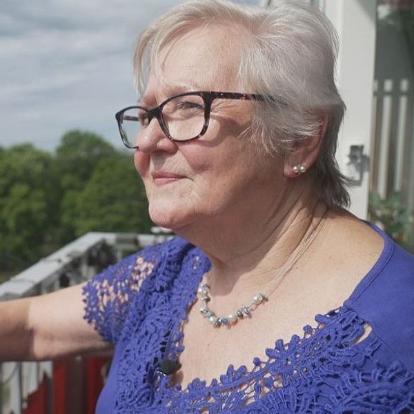 Mari Källman står på balkongen till sin nybyggda lägenhet med utsikt över grönska.