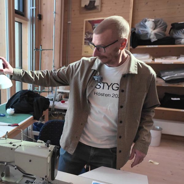 David Åkerlund visar en syateljé med symaskin och arbetsbord i bakgrund.