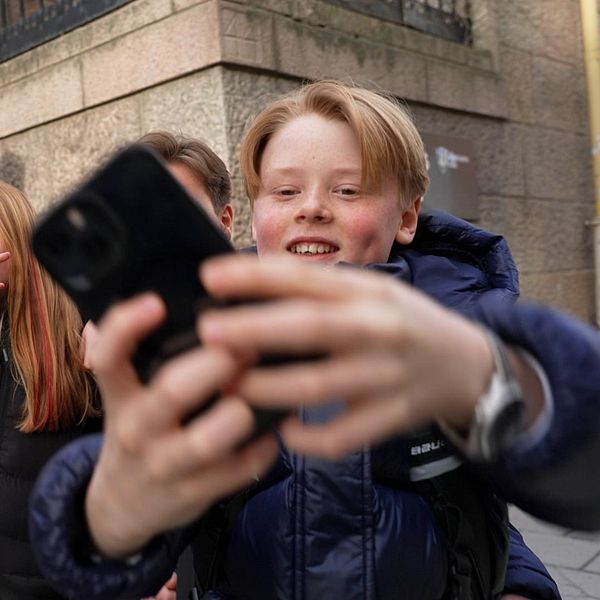 En grupp ungdomar tar en selfie på en trottoar vid en trappa.