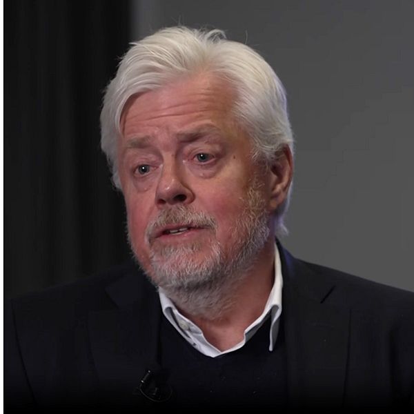 Två män i kavajer mot suddig bakgrund.