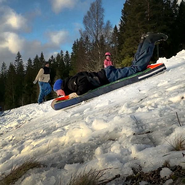 Till vänster: En person i flanellskjorta håller upp två pokaler utomhus framför en byggnad. Till höger: En person åker liggande på en madrass eller liknande föremål ner för en snötäckt sluttning medan andra människor går i bakgrunden.