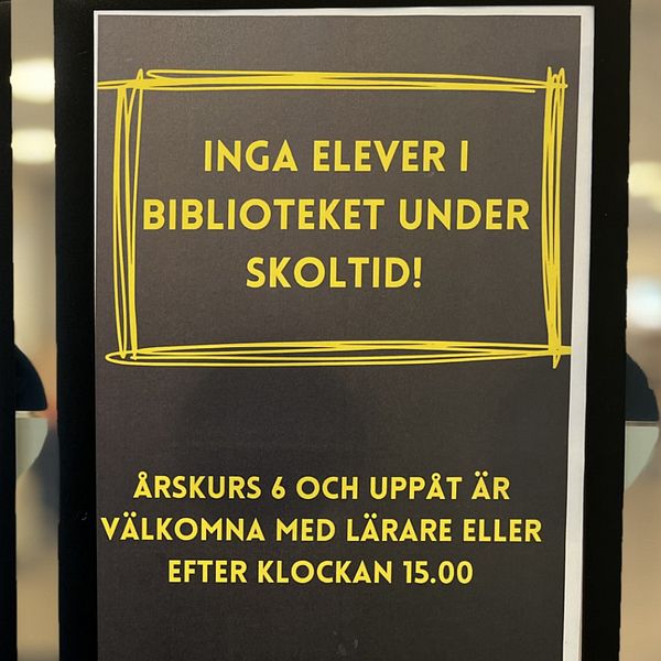 En kvinna till vänster i uppsatt hår och skjorta, till höger en svart lapp med gul text i Kortedala bibliotek.