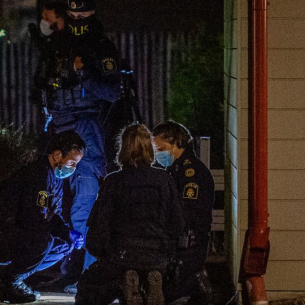 Flera poliser undersöker brottsplatsen i Klippan med ficklampor nattetid.