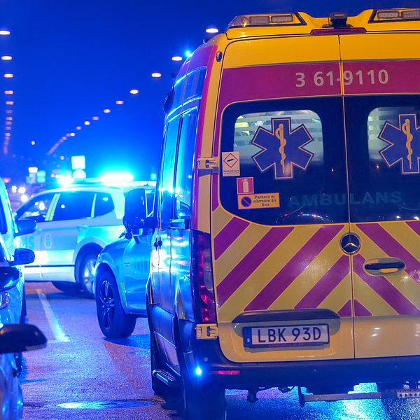 En delad bild som visar två scener. Till vänster ses en person i uniform, med en medalj och mikrofon. Till höger syns en ambulans med blinkande blåljus, parkerad på en väg med flera bilar i bakgrunden under nattens mörker.