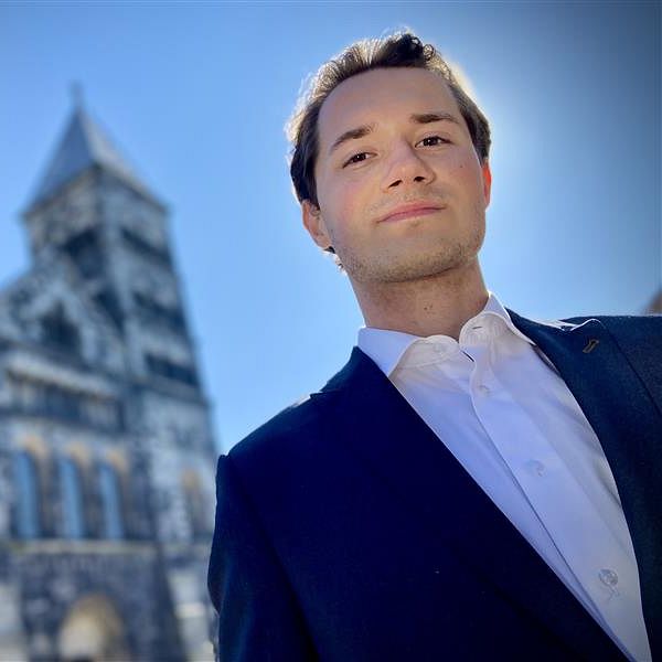 Lundastudenten Elliot Berggren från Kreditkassan framför domkyrkan i soligt väder.