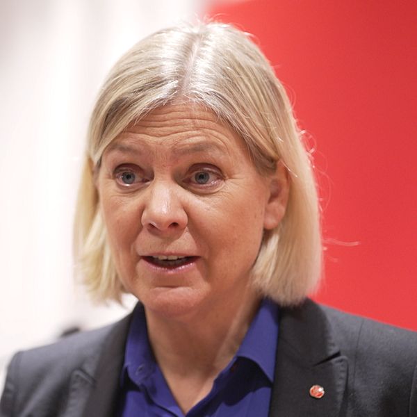 Blond kvinna med når ner till nacken iklädd mörk kavaj med Socialdemokraterna-pin och lila skjorta
