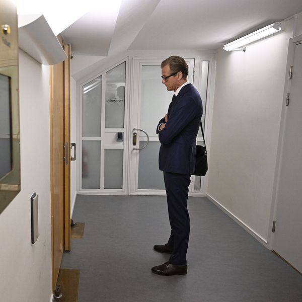 Max Ahlgren står i en korridor utanför rättssalen