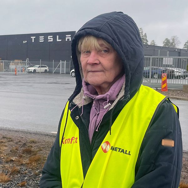 En kvinna som står vid en Tesla anläggning i Jönköping