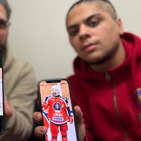 Två personer sitter tillsammans och håller upp sina mobiltelefoner. Den vänstra telefonen visar en bild av en person som ligger i säng med en bandage runt huvudet, medan den högra telefonen visar en bild av en hockeyspelare i röd uniform.