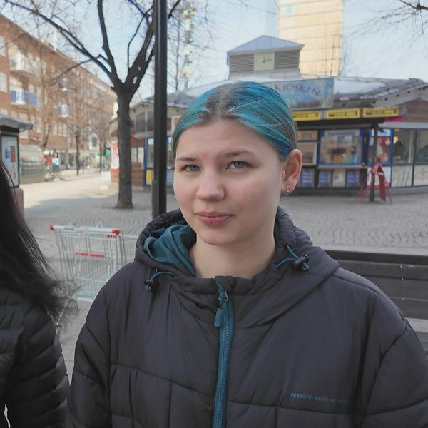 Elin Karlsson och Andrea Arklöf står på stadsgata i Skellefteå med butiker och ett träd i bakgrunden.