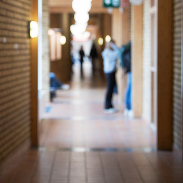 Tom skolgång med suddiga elever i korridor, symbol för våld i skolan