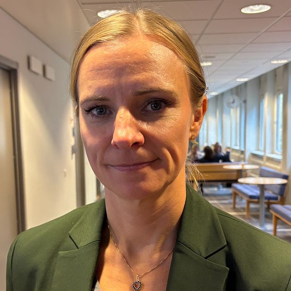 Två kvinnor i rättssal, en med brun hår och en blond i grön kavaj