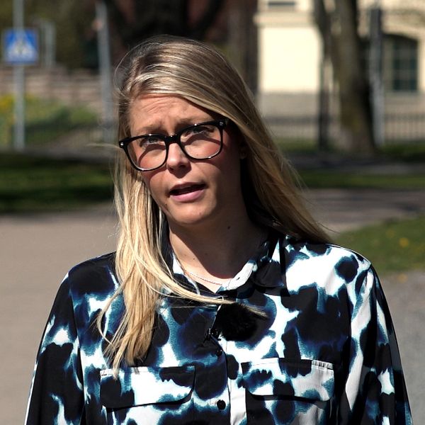 Bilden är delad i två. Den vänstra bilden är en bild på Region Sörmlands logotyp på en husfasad. Den högra bilden är en bild på SVT:s reporter Fanny Asplund. En blond kvinna i 30-årsåldern. Hon har på sig en blåmönstrad blus och glasögon med svarta bågar.