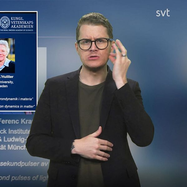 Programledare Magnus vid en bild på fysikpristagarna