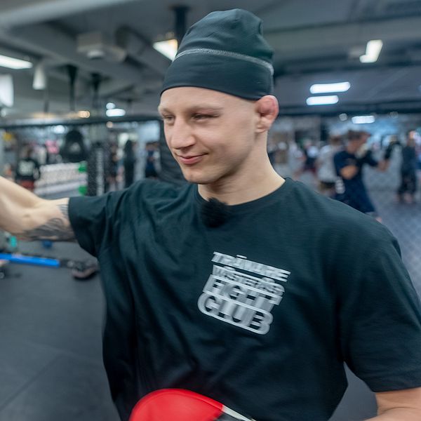 Person sparkar mot en handske på kampsportträning.