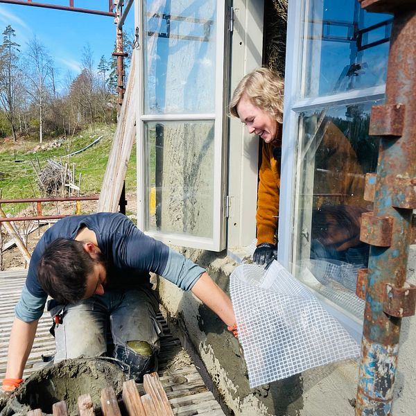 Två personer som bygger ett hus med väggar av halm och lera på Orust.