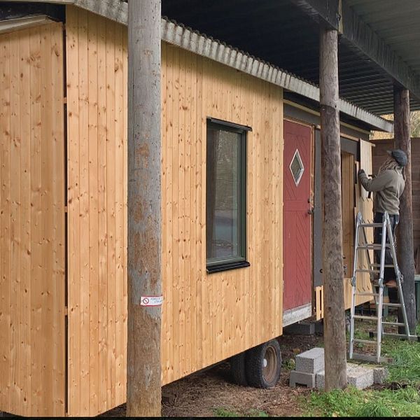 Kvinna till vänster. Till höger bild på ett litet hus.