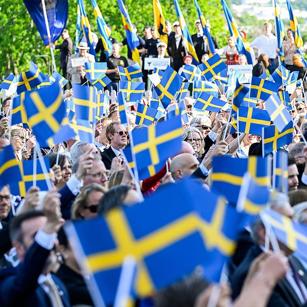 Man som blåser ut rök och en grupp människor som viftar med svenska flaggor.
