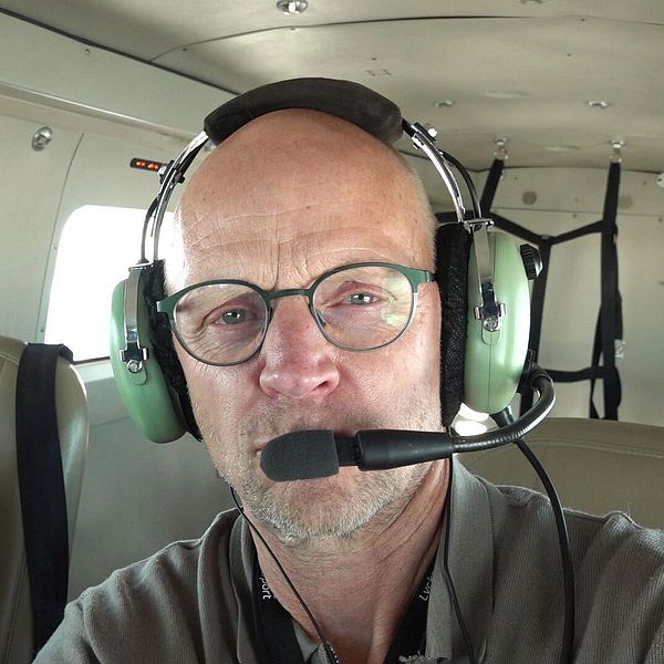 SVT:s reporter Fredrik sitter i ett flygplan. Skogen skannas av flygplanet.