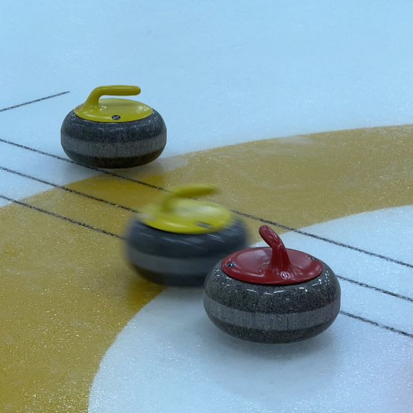 Curlingstenar och en man med keps i en hall