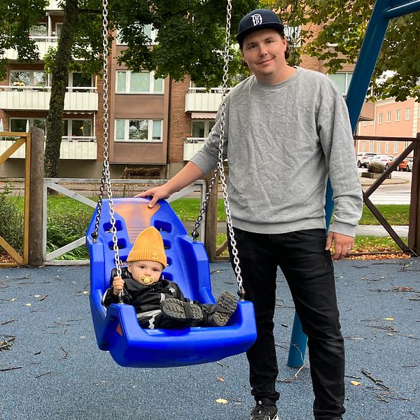 Pappa med barn i lekparken som sitter i varsin gunga.