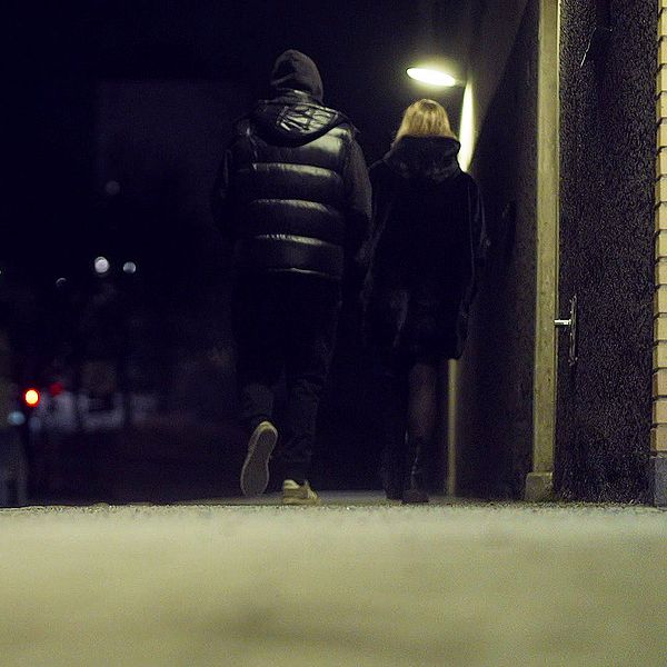 Två personer gåendes på gata i mörker.