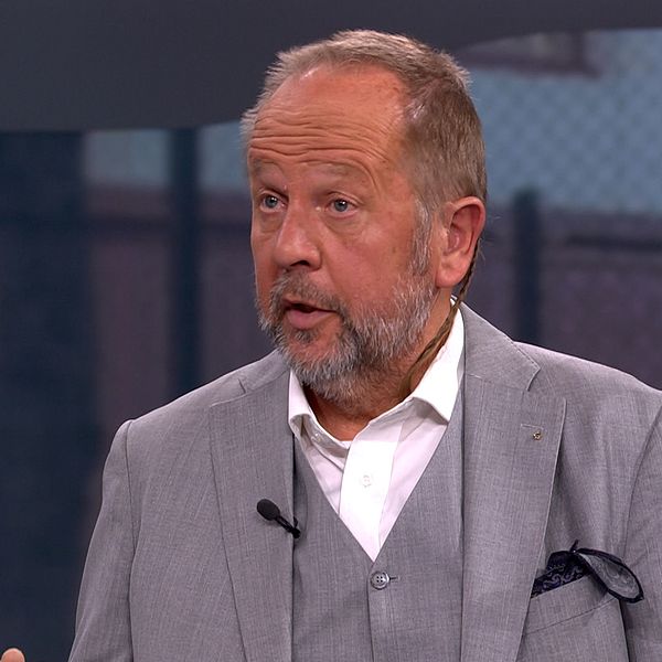 Delad bild. Två män står i studio, en i blå skjorta och svart kavaj, en i ljusgrå kostym.