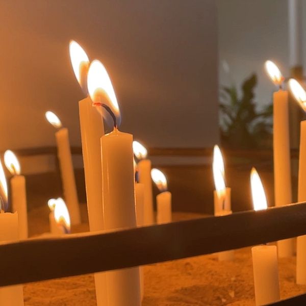 Kyrkogårdsarbetare i reflexjacka och tända ljus under allhelgona i Norrköping