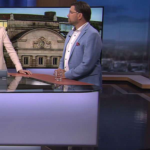 Tre personer i TV-studio runt ett nyhetsbord under sändning