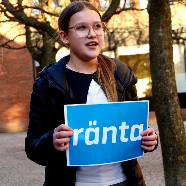 Ett barn som håller i en skylt där det står ”ränta”.