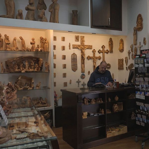 Kyrktorn och butiksägaren Jack Giacaman i en tom butik som säljer kristna föremål i trä