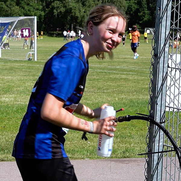 Tjej i fotbollskläder som fyller sin vattenflaska.