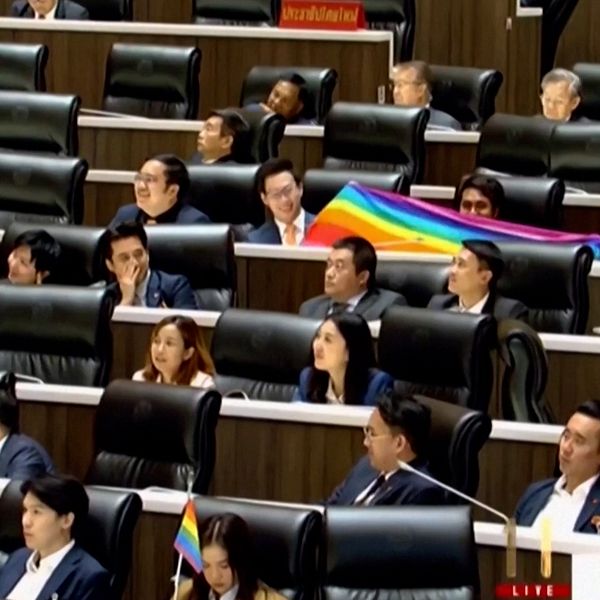 Bild på thailändare som ger kommentar på parlamentets omröstning. På bilden till höger syns parlamentsledamöter som håller i en prideflagga.