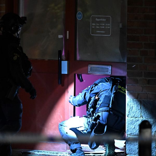 Två poliser undersöker en port i mörker efter explosion i Gamlestaden, Göteborg.