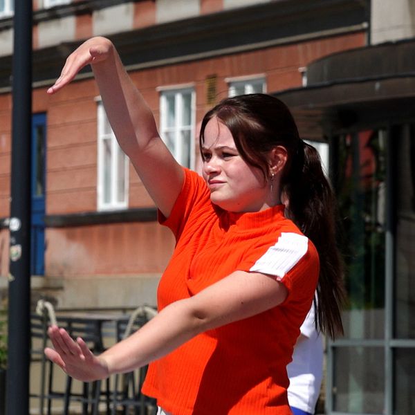 Två unga kvinnor deltar i sommardans utomhus under en solig dag.