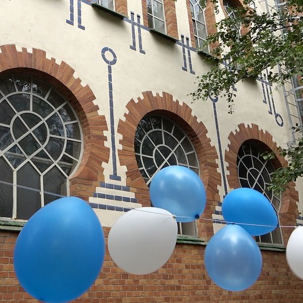 En man med kippa i Malmö synagoga och ballonger utanför synagogan