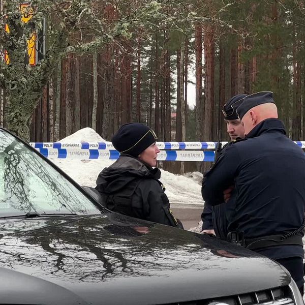 Kvinna med glasögon och poliser vid avspärrningar.