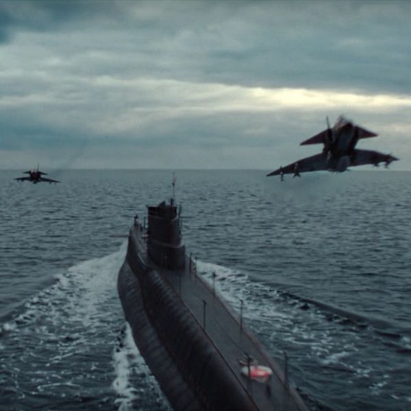 En delad bild som visar två scener: till vänster en man i kostym som pratar i telefon, och till höger en ubåt som navigerar i havet med två stridsflygplan i luften ovanför.