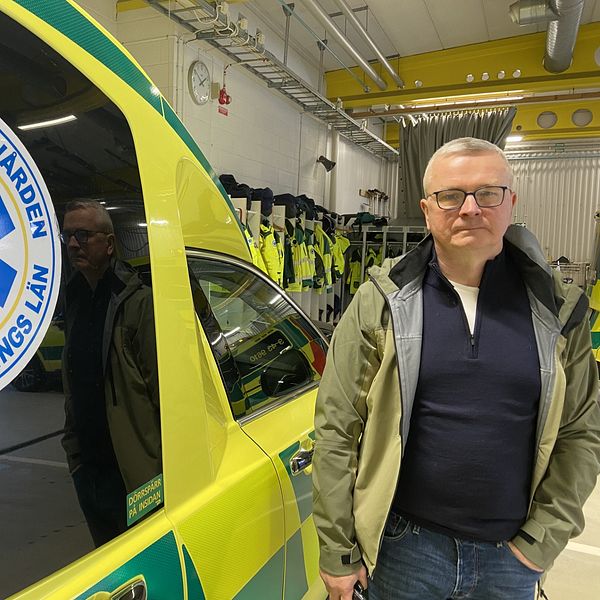 Anders Ingvarsson står bredvid en ambulans från Region Jönköpings län. Han tittar allvarligt in i kameran.
