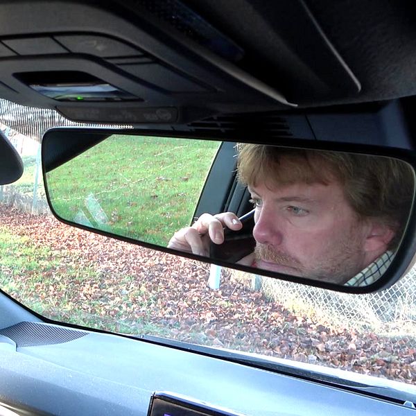 En delad bild som visar två sektioner. Den vänstra sektionen visar en stor gyllene krona installerad på en stolpe i en rondell omgiven av grönska och bilar. Den högra sektionen visar en bilinteriör med fokus på backspeglen där en person syns som använder en mobiltelefon medan de sitter i bilen.
