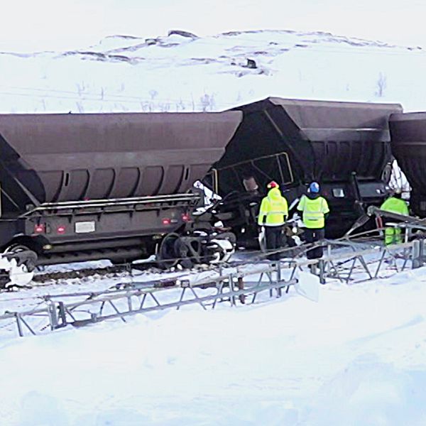 Fyra personer jobbar vid de urspårade vagnarna på Malmbanan i Vassijaure.