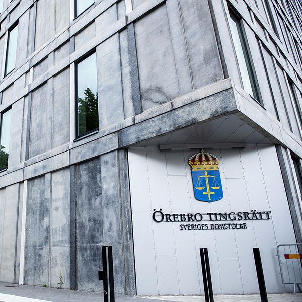 Bilden visar ett stort grått hus med stora fönster, på sidan står det Örebro tingsrätt Sveriges domstol.